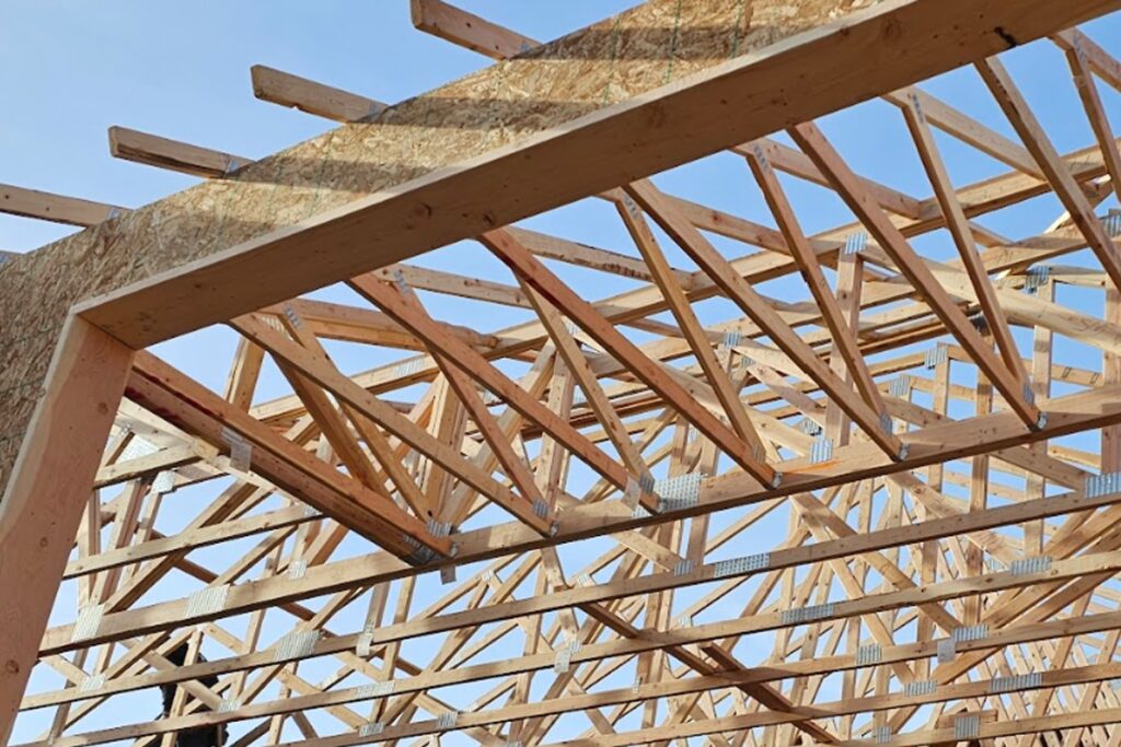 Close-up view of wooden trusses forming the roof structure of a building under construction.