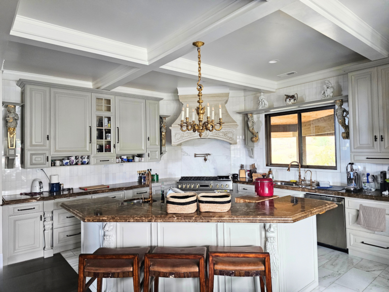 Elegant kitchen with gray cabinets, a large marble island, and gold chandelier, showcasing high-end home remodeling design.