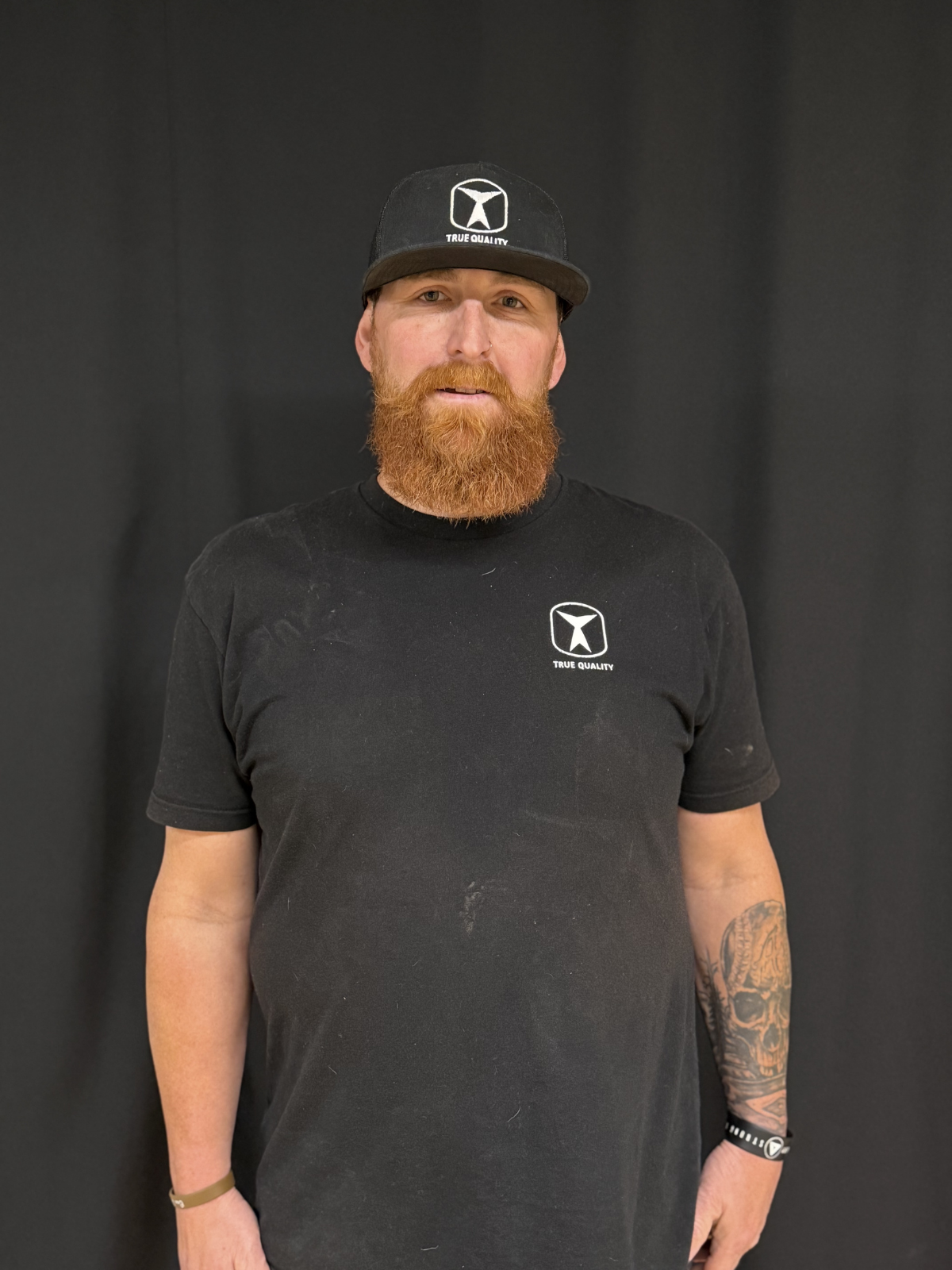 Taylor Peterson, Master Carpenter at True Quality Construction, smiling in a branded company shirt.
