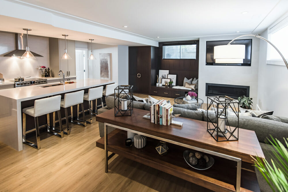 Finished basement with open-concept kitchen, white island with bar seating, fireplace, and dark wood built-ins