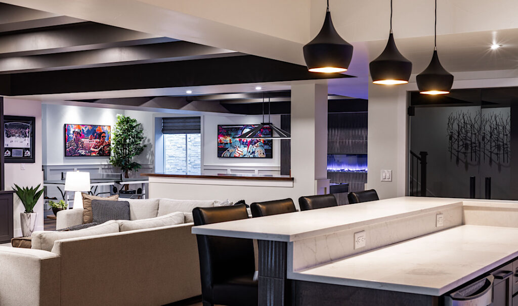 Modern finished basement with marble bar, black pendant lights, exposed beams, and built-in fireplace