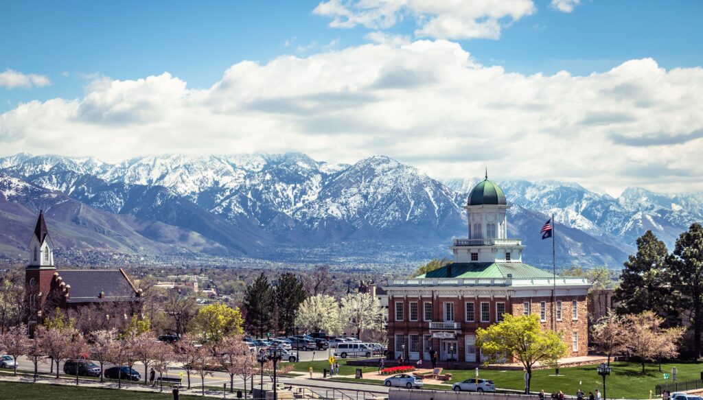 Historic domed building in Heber City, UT. with a green roof set against a backdrop of snow-capped mountains.